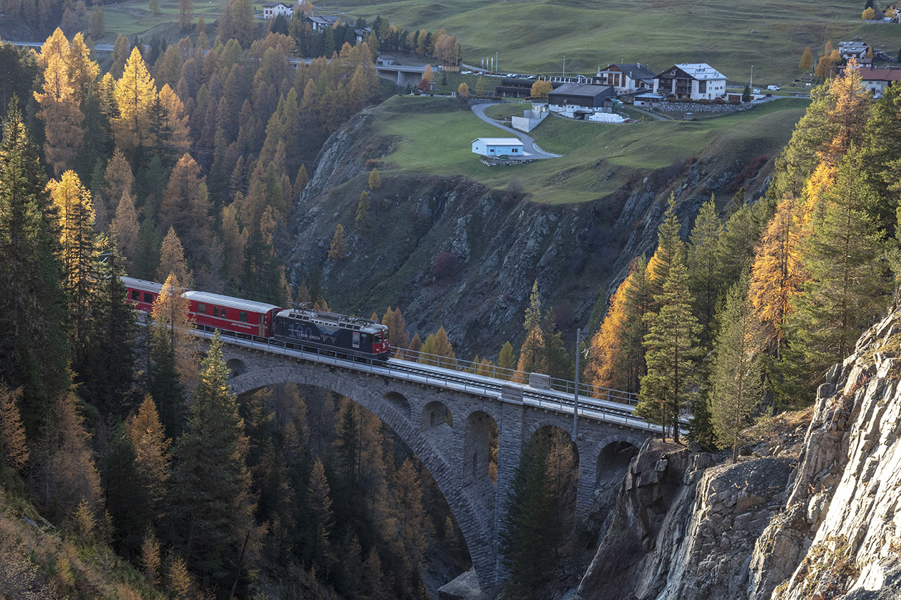 Rhätische Bahn fährt über Brücke im Herbstwald, Unterengadin, Graubünden, Schweiz